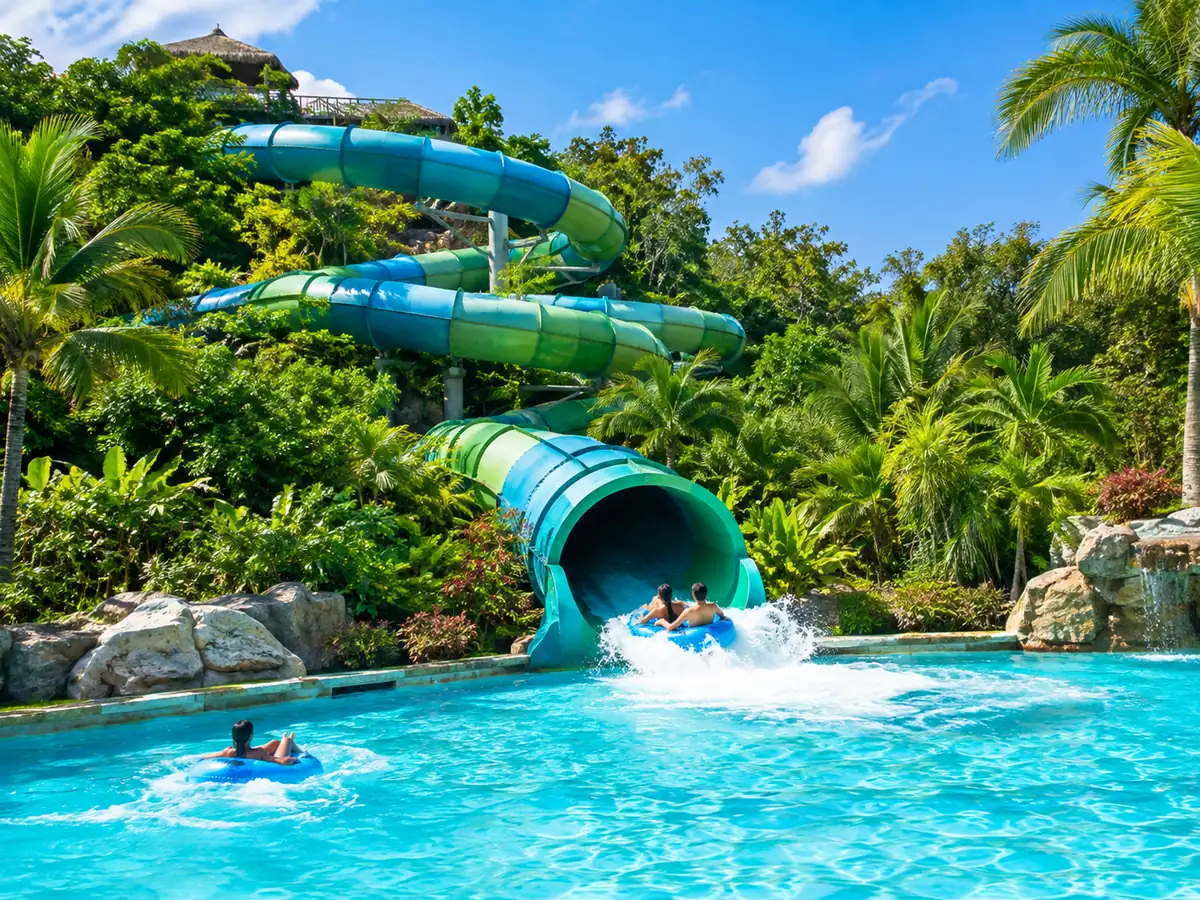 Giant tube water slide ending in a turquoise wave pool in the jungle